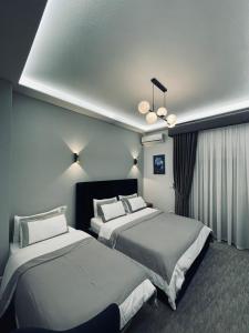 Habitación de hotel con 2 camas y lámpara de araña. en Garden Boutique Hotel en Elbasan