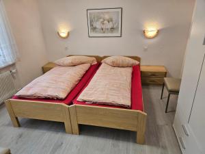 um quarto com 2 camas e lençóis vermelhos em Haus Apollo em Saas-Almagell