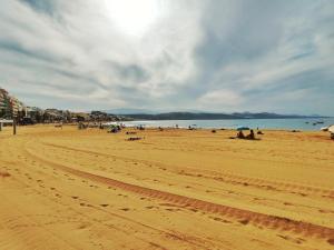 a beach with people sitting on the sand and the ocean at Sausalito Canteras by Canarias Homelidays in Las Palmas de Gran Canaria