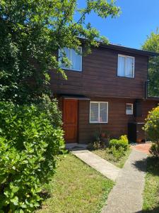 a house with a wooden door and a yard at Cabaña Villa Reina Sofia in Valdivia