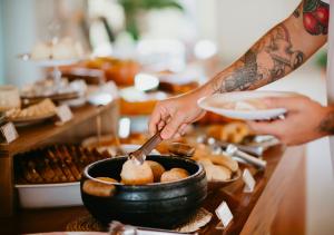 a person is preparing food in a bowl on a table at Hotel Chalé Capitólio in Capitólio