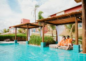 a couple sitting on the edge of a swimming pool at a resort at Hotel Chalé Capitólio in Capitólio