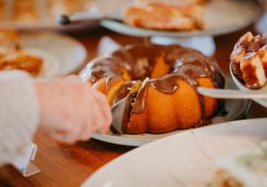 a person reaching for a chocolate bundt cake on a table at Hotel Chalé Capitólio in Capitólio