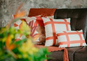a brown couch with orange and white pillows on it at Hotel Chalé Capitólio in Capitólio