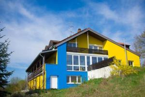 une maison jaune et bleue au sommet d'une colline dans l'établissement Großes Panorama Haus für Freunde, à Pottenstein