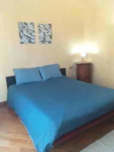 uma grande cama azul num quarto com um candeeiro em Casa Patrone appartamento Luigi em Nebbiuno