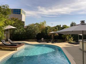 a swimming pool with chairs and umbrellas and a building at Hôtel Restaurant Le Clos des Tanneurs romans sur Isère in Romans-sur-Isère