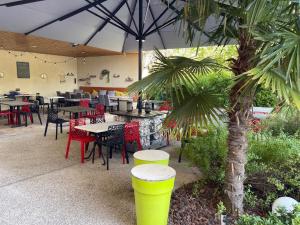 a restaurant with tables and chairs and a palm tree at Hôtel Restaurant Le Clos des Tanneurs romans sur Isère in Romans-sur-Isère