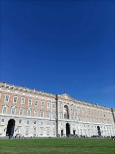 een groot gebouw met mensen die ervoor staan bij Maison La Reggia in Caserta