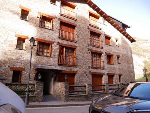 a brick building with balconies and a car parked in front at Francoli-Vacances Pirinenca in Canillo