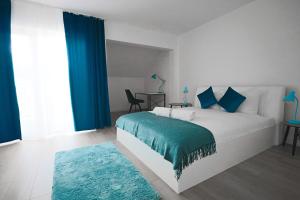 1 dormitorio con cama blanca con sábanas azules y alfombra azul en Reymonta 22 Apartamenty en Opole