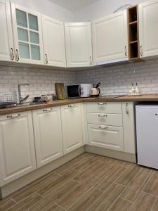 a white kitchen with white cabinets and a microwave at Apartman Alexandra in Ruma