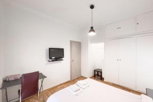 Habitación blanca con escritorio y TV en la pared. en Cozy Cityscape Apartment in Athens en Athens