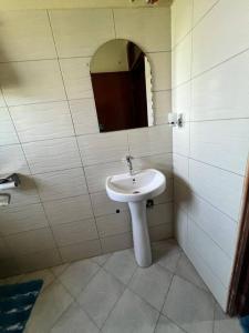 a bathroom with a white sink and a mirror at Home in Kira Namugongo. in Kira