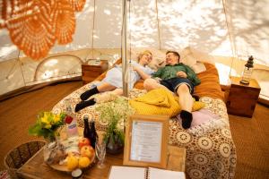 two people laying on a bed in a tent at Karkausmäki Glamping in Kinnula