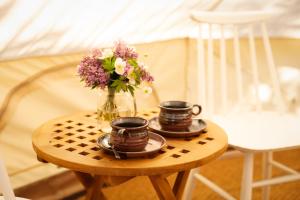 einen Tisch mit zwei Tassen und einer Vase Blumen in der Unterkunft Karkausmäki Glamping in Kinnula