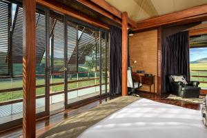 a bedroom with a bed and large windows at Zulu Waters Game Reserve in Estcourt