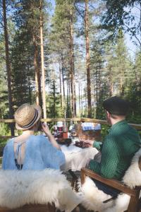 a man and woman sitting at a table with sheep at Karkausmäki Glamping in Kinnula