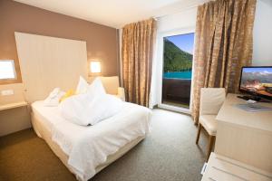 a hotel room with a bed and a desk and a window at Hotel Vernagt in Senales