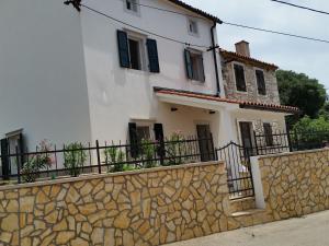 a white house with black windows and a stone wall at Holiday Home Casa Matilde in Koromačno
