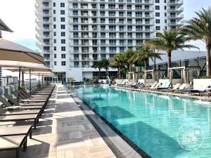 una piscina con tumbonas y un gran edificio en Luxury apartment with endless ocean views -Daily resort fee and parking not included- en Hollywood