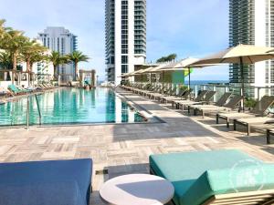 una piscina con sillas y sombrillas en un edificio en Luxury apartment with endless ocean views -Daily resort fee and parking not included-, en Hollywood