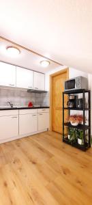 a kitchen with white cabinets and a wooden floor at Gemütliches Apartment am Gottesberg in Muldenhammer