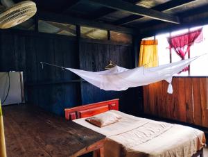 Un dormitorio con una cama y una red colgando del techo en Hospedaje y tours Reina Arriera amazonas colombia, en Macedonia