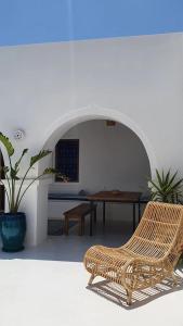 a wicker chair sitting in a room with a table at Maison d’hôte, Djerba 