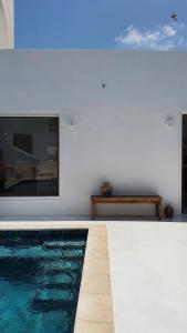 a swimming pool next to a white wall with a painting at Maison d’hôte, Djerba 