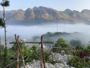 una vista di una montagna nebbiosa con una croce di Du Già Coffee View Homestay a Làng Cac