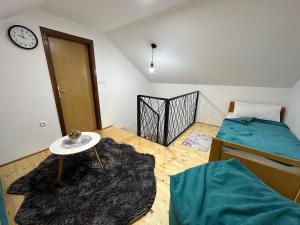 - une chambre avec un lit, une table et une horloge dans l'établissement Snjezna kuca Rakovac, à Pale