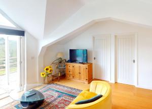 a living room with a yellow couch and a tv at Georgeham Sweet Pea Cottage in Georgeham