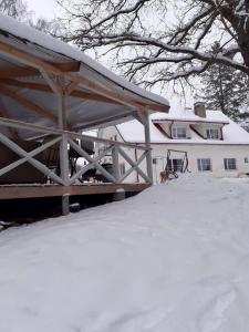 ein Haus mit Schnee auf dem Boden davor in der Unterkunft Vana-Vastseliina külalistemaja in Illi