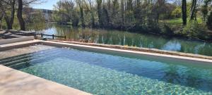 a large swimming pool next to a river at La Magnanerie d'Hôtes ,le jardin secret in Sauve