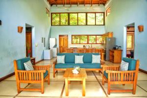 ein Wohnzimmer mit einem blauen Sofa und Stühlen in der Unterkunft Cañafistula Fourth Dimension in Tamarindo
