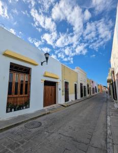 une rue vide avec des bâtiments blancs et un ciel bleu dans l'établissement Casa Aguazul, à Campeche
