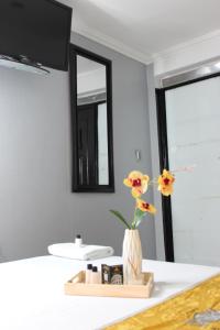 a bathroom with a mirror and a vase with flowers at Hotel WC in Bogotá
