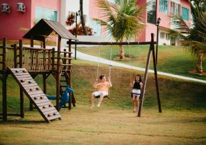 two girls playing on a swing in a park at Hotel Chalé Capitólio in Capitólio