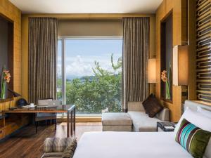 um quarto de hotel com uma cama, uma secretária e uma grande janela em The Olympian Hong Kong em Hong Kong