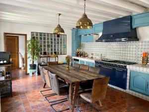 a kitchen with a wooden table and blue cabinets at Le Clos Papillon in Corcelles-les-Monts