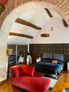 a bedroom with a bed and a red couch at Le Clos Papillon in Corcelles-les-Monts