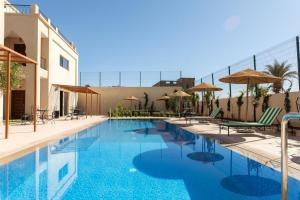 瓦爾扎扎特的住宿－Maison D'hôtes IMINIGRAN & Spa，一座带椅子和遮阳伞的游泳池位于一座建筑旁边