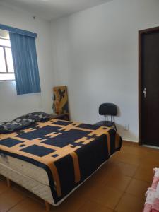 a bedroom with a bed and a chair in it at Casa com piscina em Bertioga in Bertioga