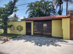 a garage with a yellow building with a red roof at Casa com piscina em Bertioga in Bertioga +1 photo