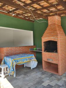 a brick oven with a table in a room at Casa com piscina em Bertioga in Bertioga