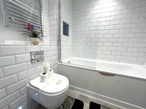 a white bathroom with a toilet and a bath tub at Albert Road, Bournemouth Town in Bournemouth