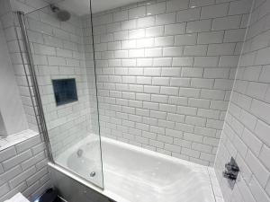 a white tiled bathroom with a shower and a tub at Albert Road, Bournemouth Town in Bournemouth