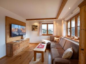 ein Wohnzimmer mit einem Sofa und einem TV in der Unterkunft Apartment-Chalet Mödlinghof in Hopfgarten im Brixental