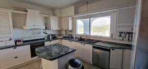 a large kitchen with white cabinets and a window at Villa Tranquila Arenas Malaga in Arenas